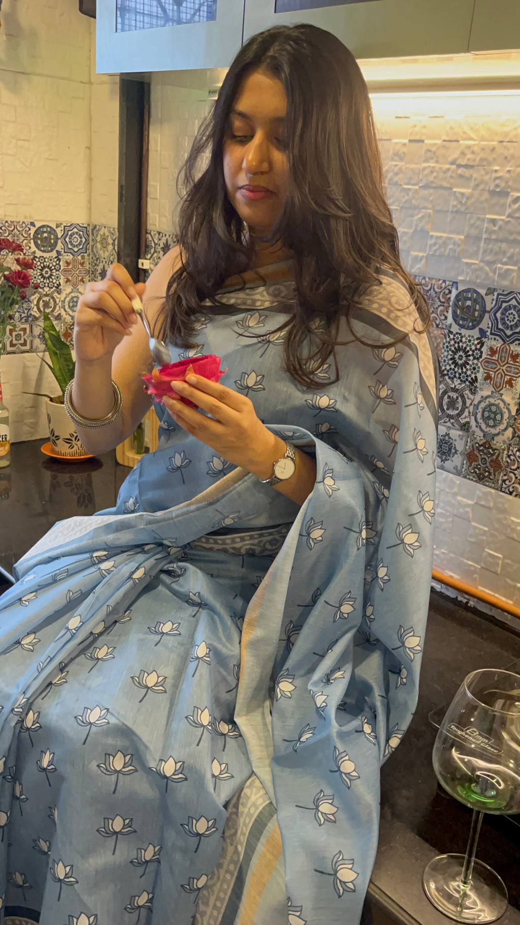 Women wearing cotton sari with lotus print. sitting in the kitchen eating dragon fruit. comfortable cotton sarees.